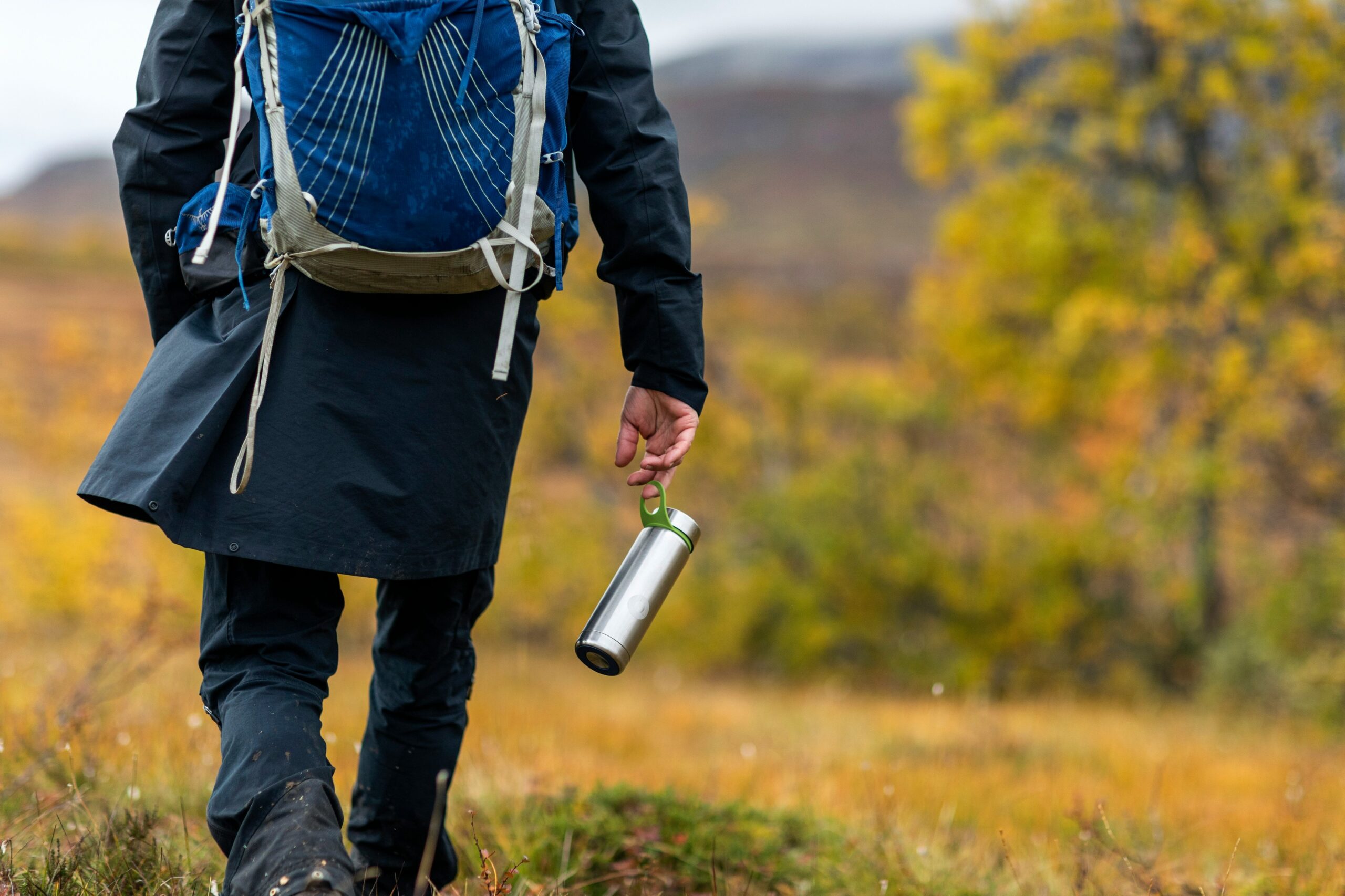 person waking while holding metal water bottle